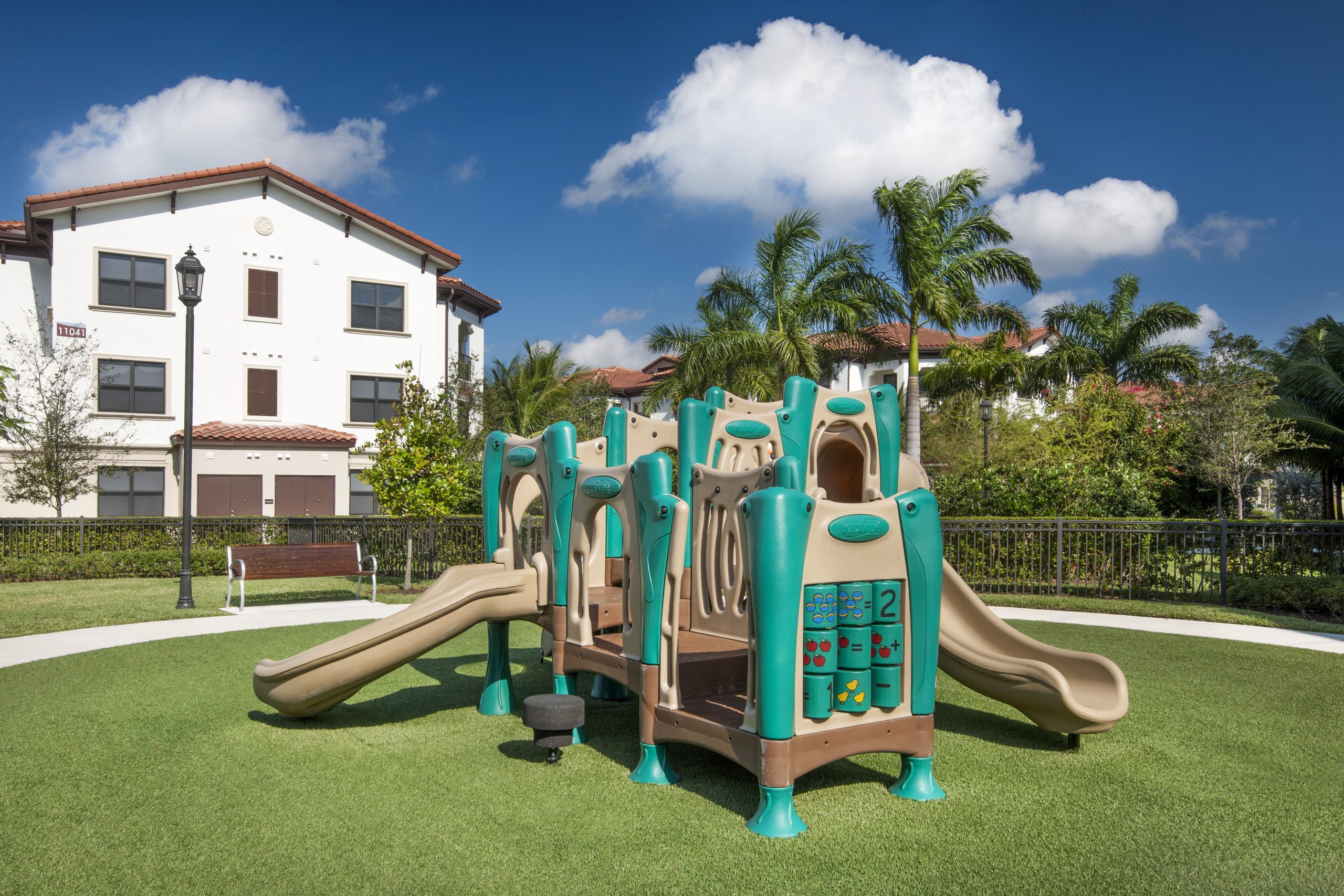 Apartments in Miramar A playground with a slide and swings in front of an apartment building. Miramar Park Apartments